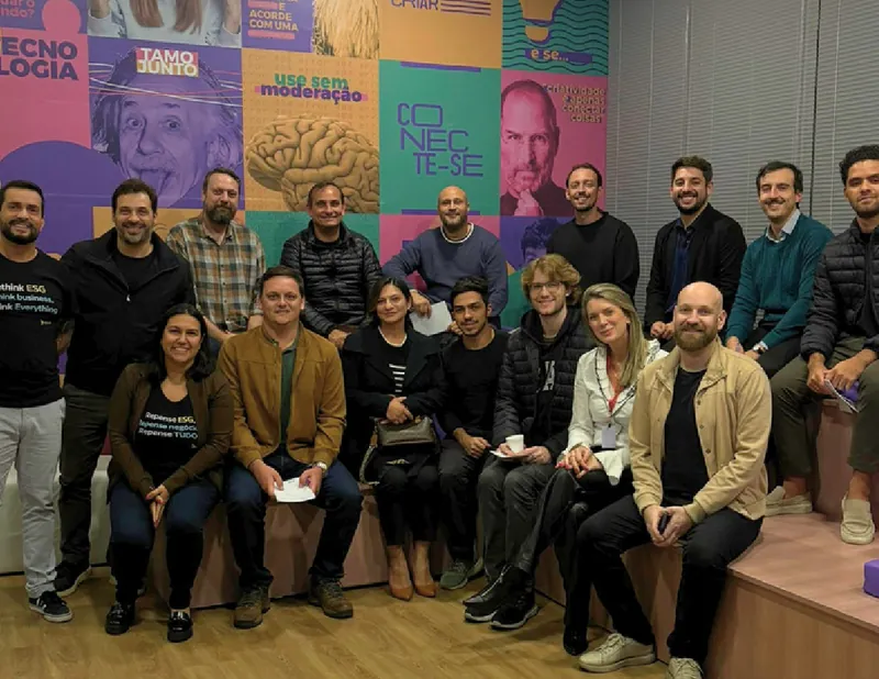 Participantes do ESG Lab no CIB Blumenau reunidos diante de uma parede com cartazes coloridos