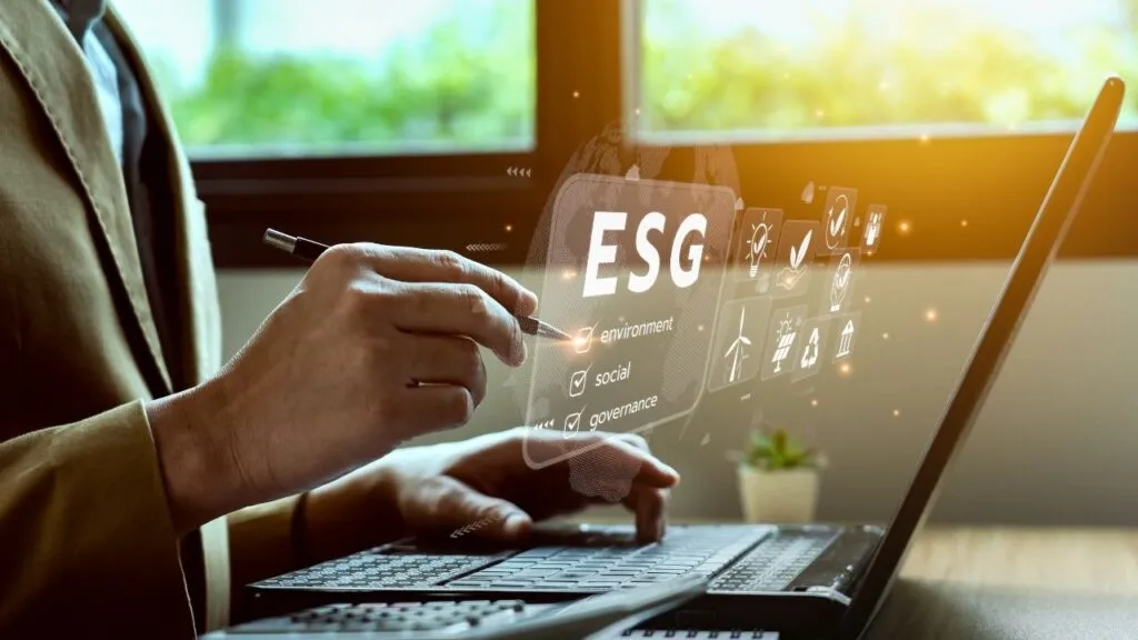 Pessoa usa um notebook com ícones digitais de ESG projetados sobre a tela